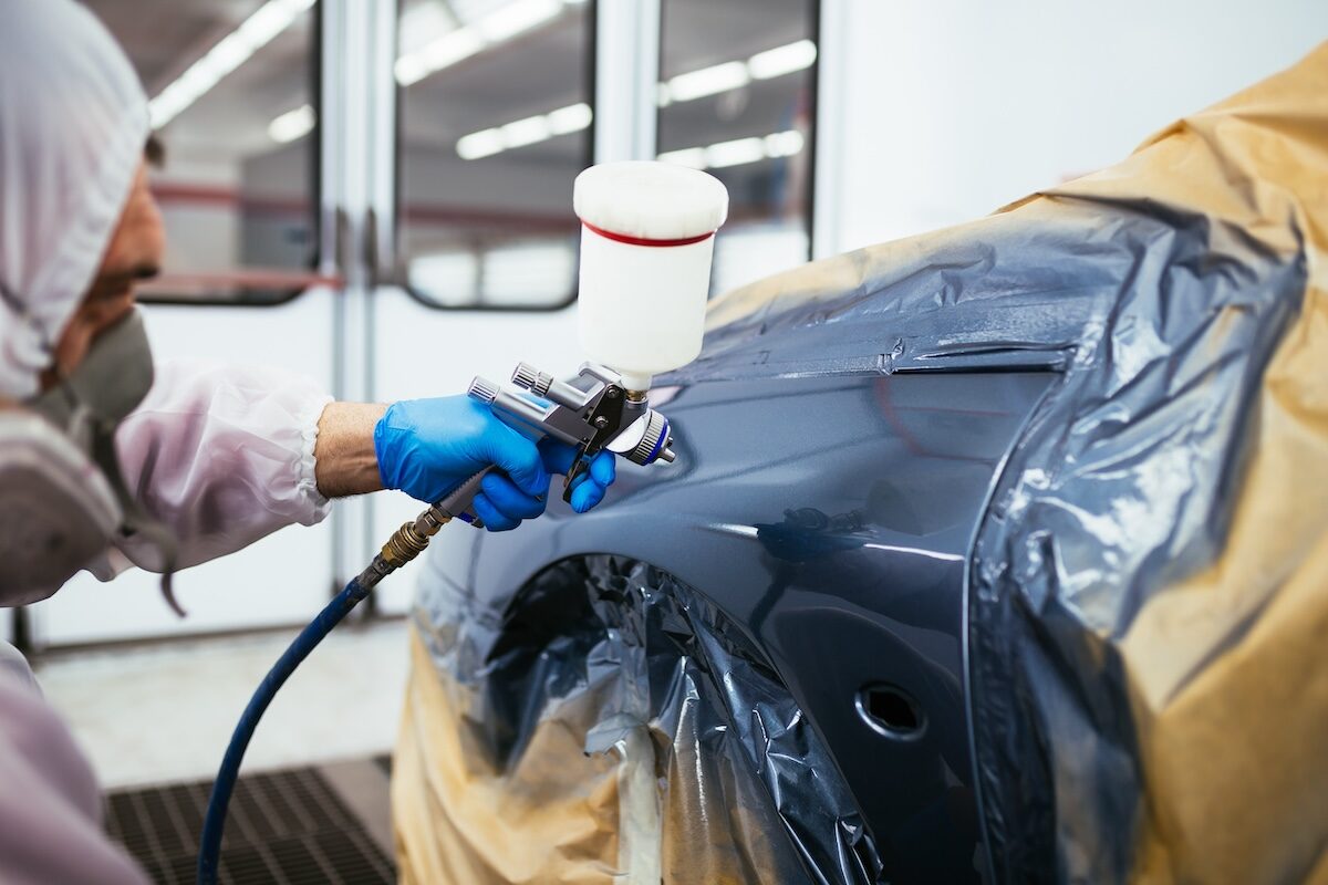 man painting car using spray compressor